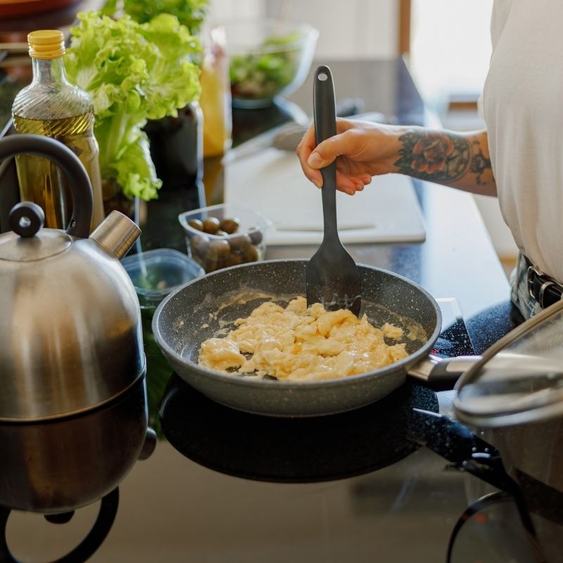 Female hands cooking an omlette in a frying pan