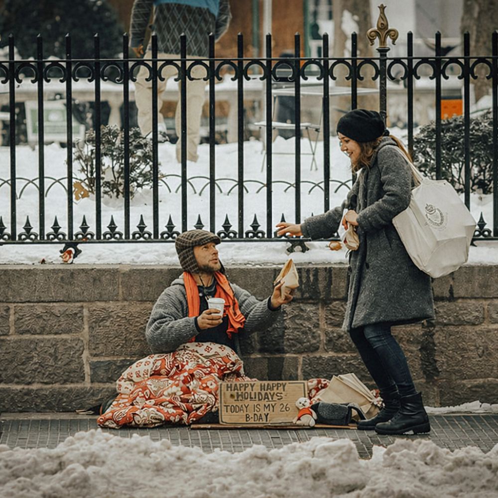 Woman offering a sandwich to a homeless man